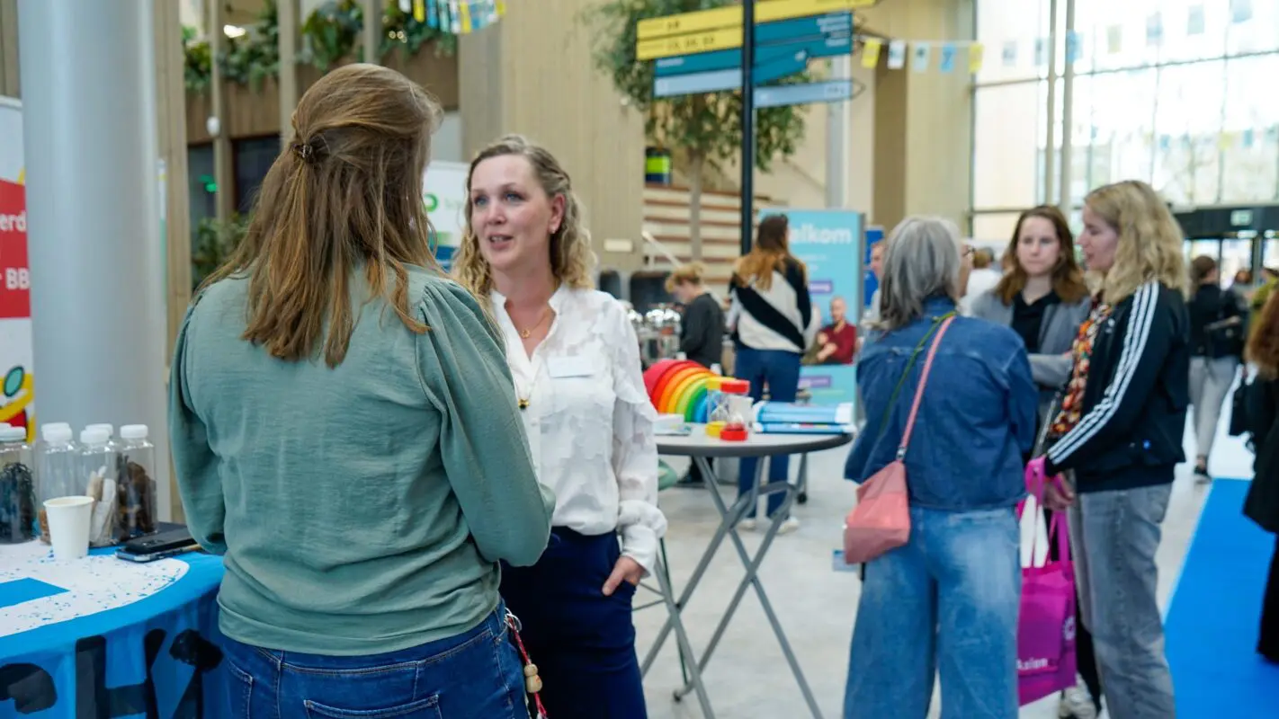 Bezoekers in de hal van MBO Utrecht in gesprek met voorlichters tijdens WerkOntdekAvond