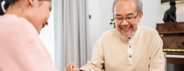 Oudere cliënt kijkt tevreden naar iets dat voor hem op tafel ligt