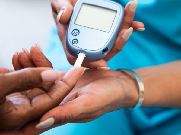 Doktersassistent neemt bloed af uit de vinger van een patiënt