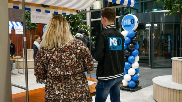 Docent en student ontvangen gasten bij de entree op de Open Dag